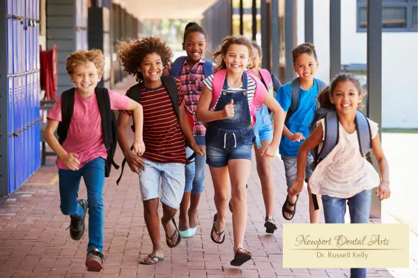 Children smiling with backpacks on the first day of school in Newport Beach, highlighting healthy teeth and back-to-school dental tips