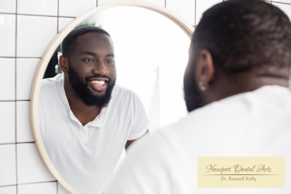 Newport Beach patient admiring new no-prep veneers in a mirror, natural bright smile